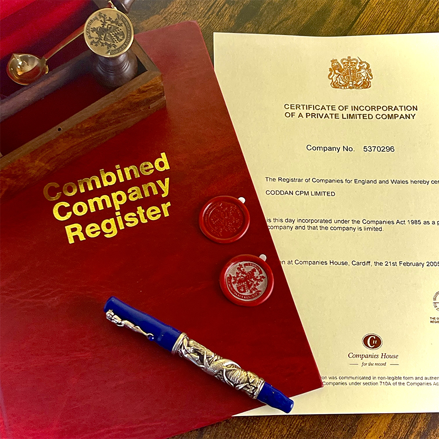 A red combined corporate register lies on a surface, accompanied by a pen and a company stamp ready for mailing. A red corporate official register displayed with a pen beside it and a business seal attached, prepared for mailing. A red combined corporate register lies on a surface, accompanied by a pen and a company stamp ready for mailing. A red corporate official register displayed with a pen beside it and a business seal attached, prepared for mailing.